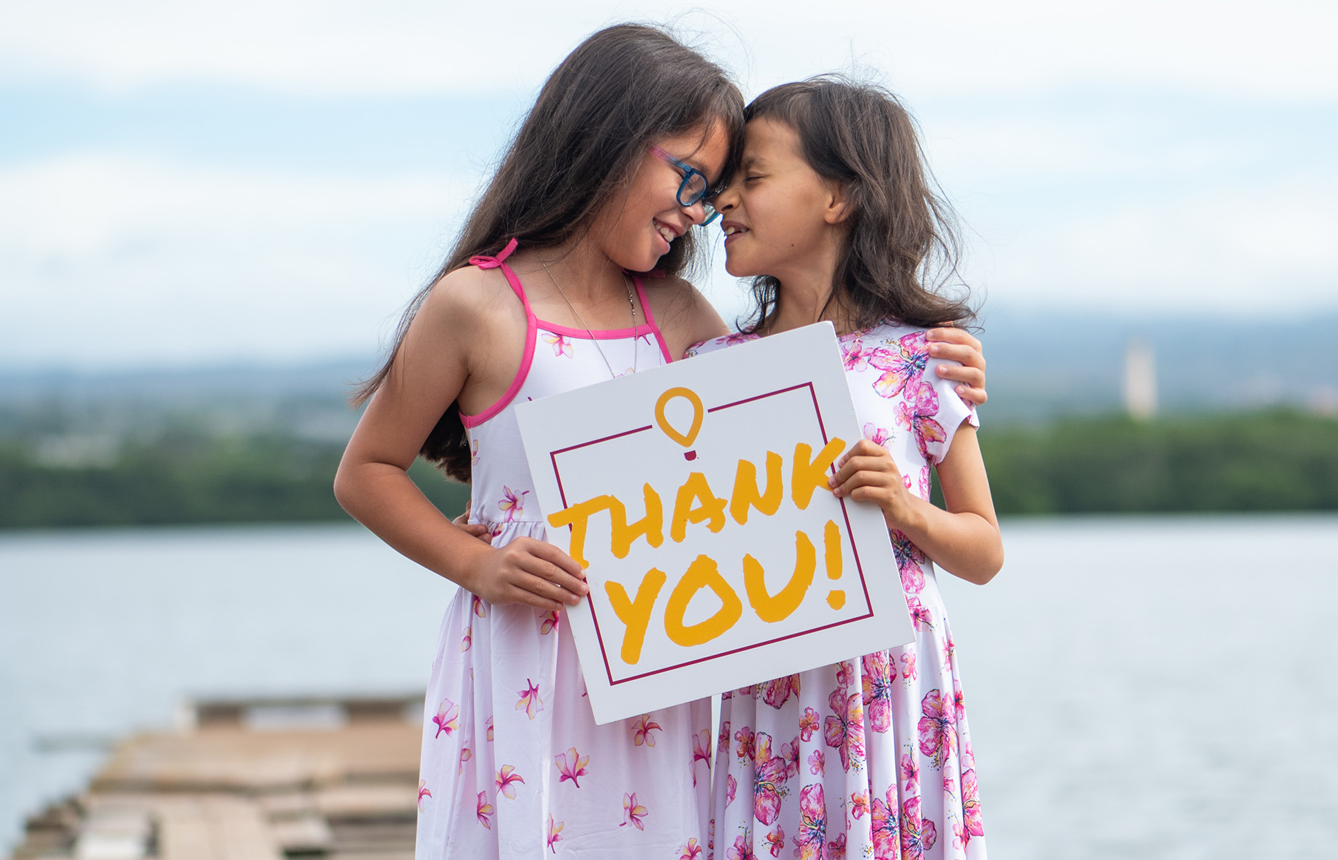 Aurelia and sister holding a thank you sign