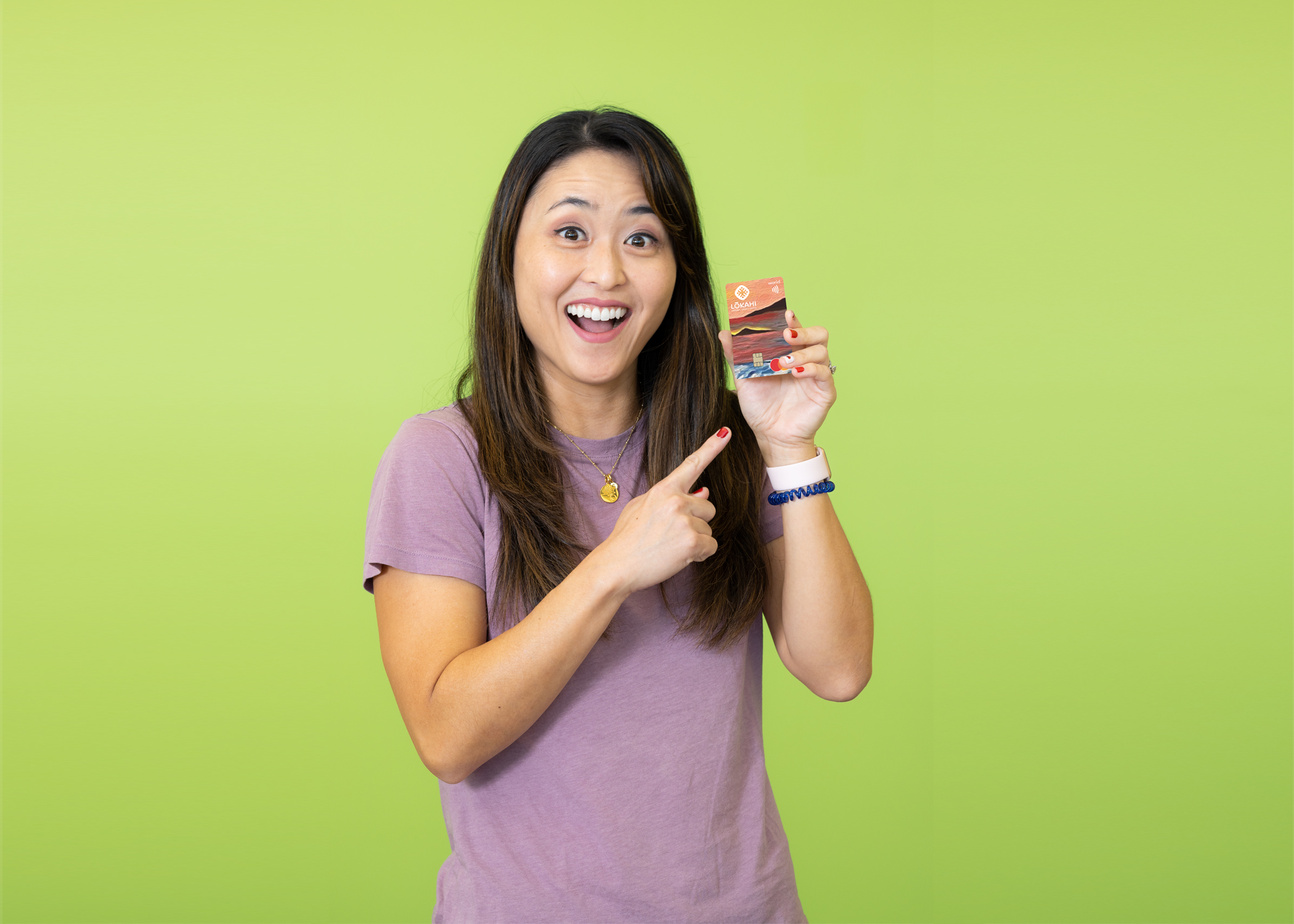 A woman holding a Lōkahi FCU World Mastercard credit card